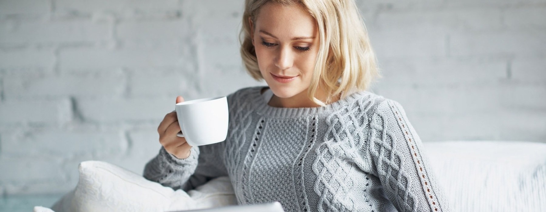 a woman holding a coffee cup looking at a tablet